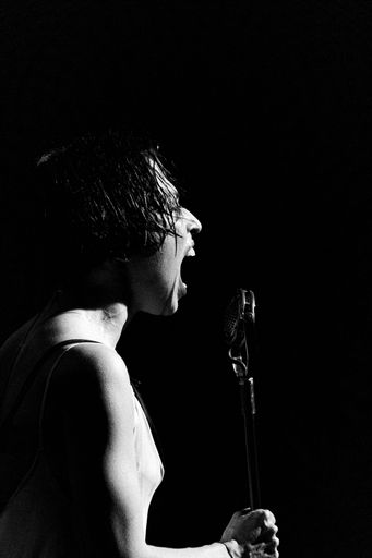 A grayscale shot of a person singing dramatically for a musical play performance