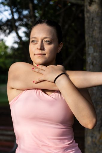 A vertical shot of a confident young woman doing arm stretches before working out in the park