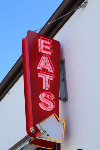 A large, vibrant red neon "eats" sign for a restaurant