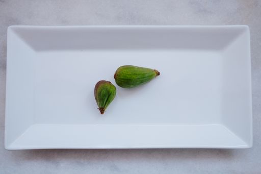 A top view of two small unripe feijoas in a plate on the table