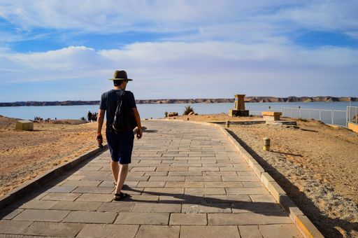 A closeup shot of a male walking on a road near the sea on a sunny day