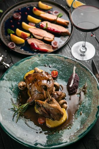 A closeup of grilled meat on plate with glass of wine