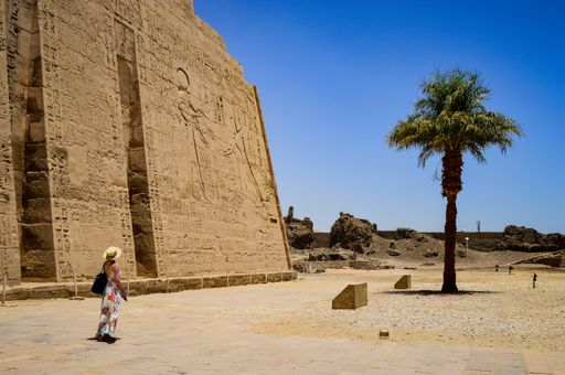 A closeup shot of a female standing in front of a Medinet Habu temple in Egypt