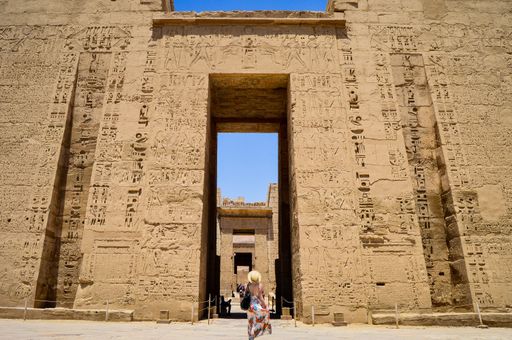 A closeup shot of a female standing in front of a Medinet Habu temple in Egypt