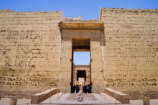 A closeup shot of a female standing in front of a Medinet Habu temple in Egypt