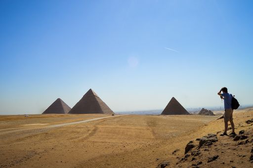 A closeup shot of a male standing and looking at Giza Necropolis in Egypt