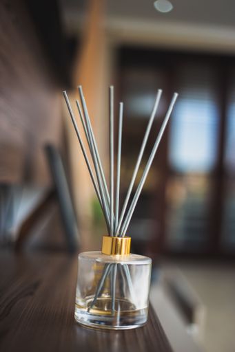 A vertical shot of reed diffuser sticks in a glass bottle on a table