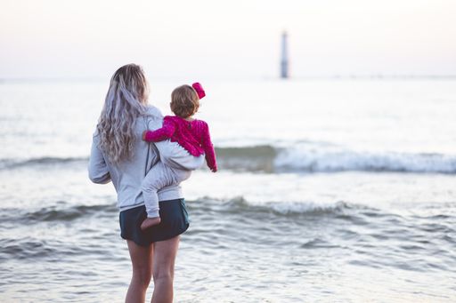A closeup focus shot from behind of a mother and her child looking at the sea