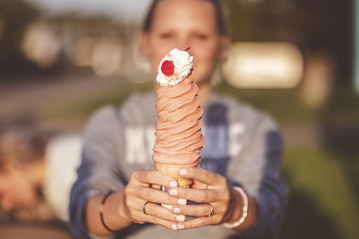 A closeup focus shot of a woman holding a tall ice cream cone