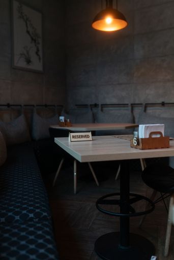A vertical shot of cozy corner of a cafe with reserved tables and dark gray walls