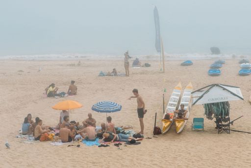 A handful of beach-goers on the beach of Cascais in Lisbon, Portugal on a gloomy day