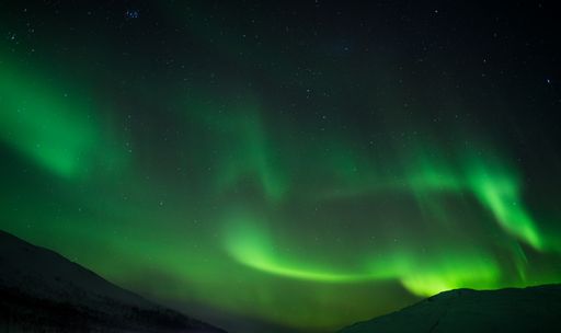 A beautiful shot of bright green aurora northern lights over mountains in Norway