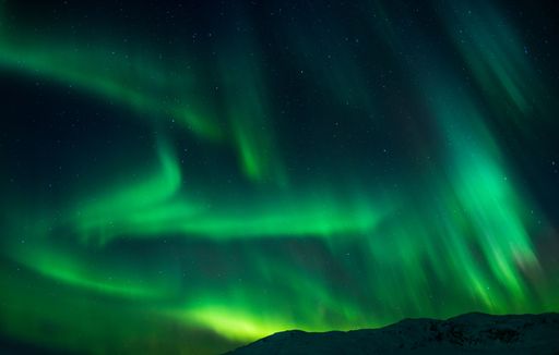 A beautiful shot of bright green aurora northern lights over mountains in Norway