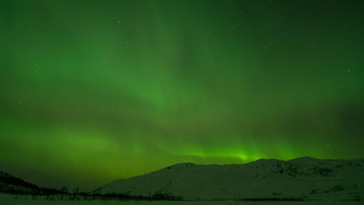 A beautiful shot of bright green aurora northern lights over mountains in Norway