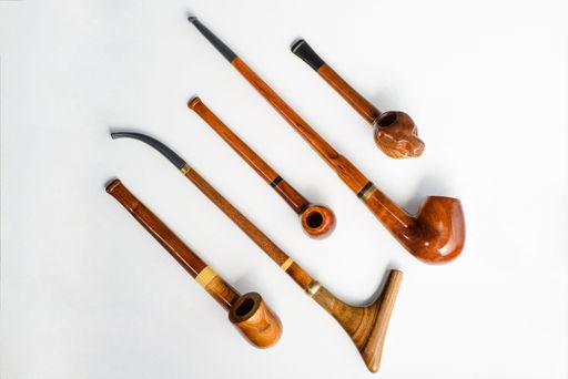 A top view of various wooden smoking pipes on a white background