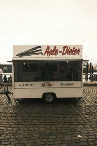 A vertical shot of a vintage one-wheel white food truck in an urban area of a city