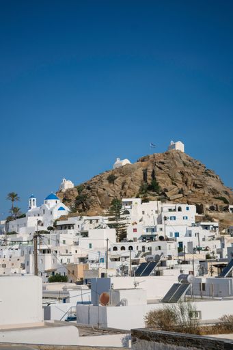 A vertical shot of typical white houses with blue sky in background, Greece