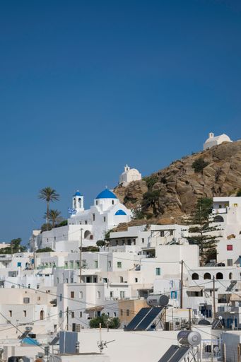 A vertical shot of typical white houses with blue sky in background, Greece