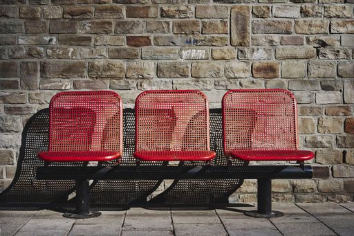 A beautiful shot of three red seats in the bus station of an urban area