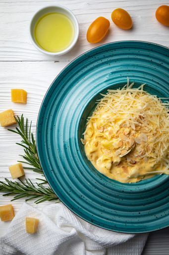 A blue ceramic bowl filled with macaroni and cheese on a white background table