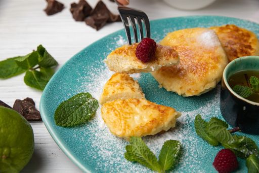 A close-up of a person eating freshly-made pancakes, topped with a selection of ripe berries