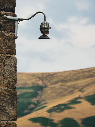 A vertical shot of an old broken gas lamp on a farm building