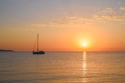 The sea with a sailboat against the beautiful background of the sky at sunset.