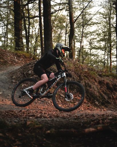 A vertical shot in action of a biker on a trail bike riding a ghost bike in the mountains of Wroclaw, Poland