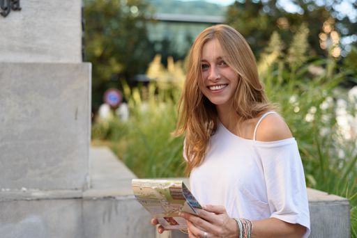 A young female trying to find a place with the help of a map on a street