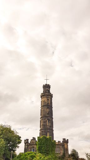 A vertical low angle shot of the Nelson Monument under the cloudy sky in Edinburgh, Scotland