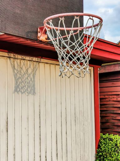 A vertical shot of a basketball hoop on a house exterior
