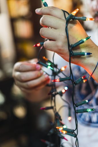 A closeup shot of a male holding Christmas lights on blurred background