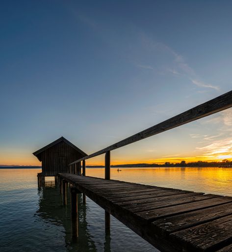 A vertical shot of a wooden boat house at a lake in Southern Germany during a beautiful sunset