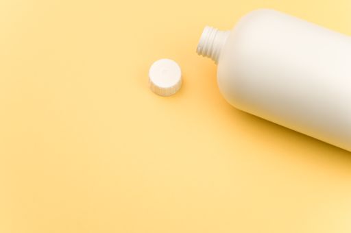 A closeup shot of a white plastic container with an open lid on a yellow surface
