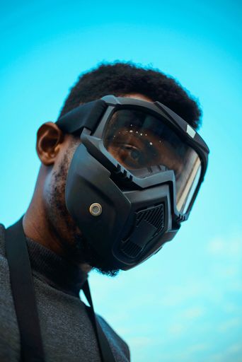 A vertical shot of a man wearing a protective mask over a blue background