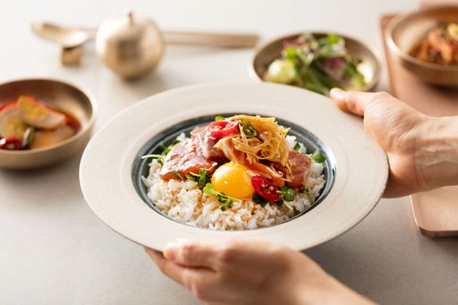A closeup shot of a white dish with rice and vegetables on the top