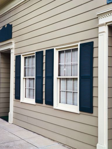 A vertical shot of white and blue windows on beige wall of modern architecture