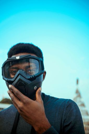 A shallow focus of a black person in a goggle mask against a blue background of sky