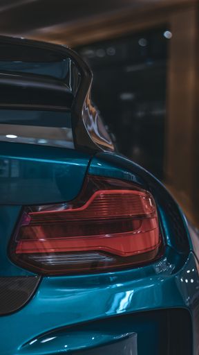 A vertical closeup shot of a rear light of a modern blue car in the salon