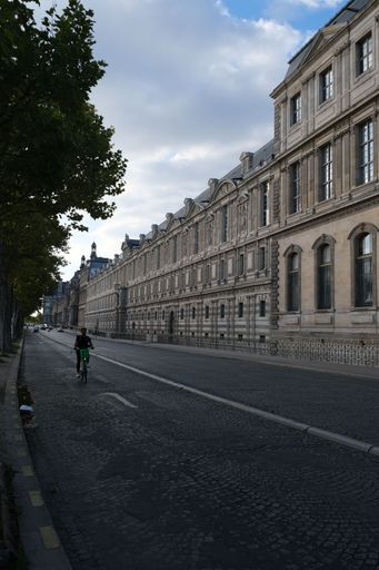 A vertical shot of side facade of the Louvre and a bike on the street in Paris, France