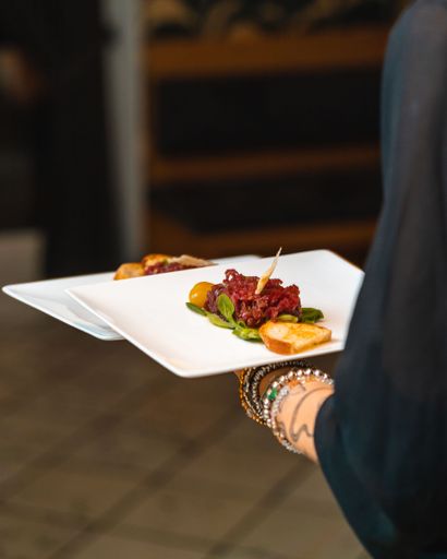 A vertical shot of a person holding a plate of beef tartare against the isolated background