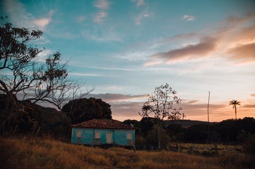 An old abandoned building in a field under a cloudy sky during the sunset