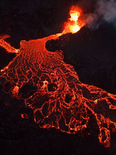 A vertical shot of lava flowing from a volcano at night in Iceland
