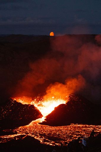 A vertical shot of lava flowing from a volcano at sunset in Iceland