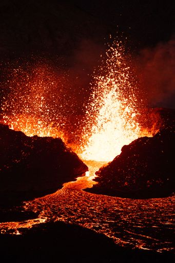 A vertical shot of lava flowing from a volcano at night in Iceland