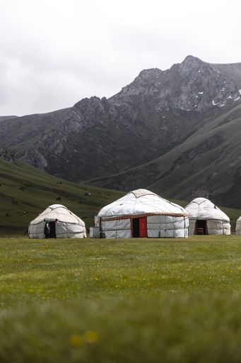 A white tent in mountain valley with a cloudy sky