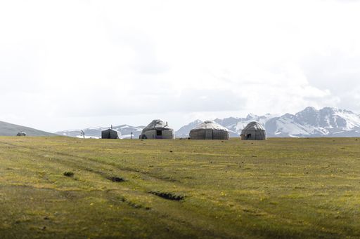 A white tent in mountain valley with a cloudy sky