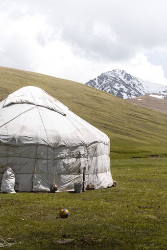 A white tent in mountain valley with a cloudy sky
