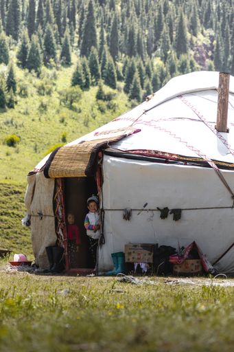 A white tent in mountain valley with a cloudy sky