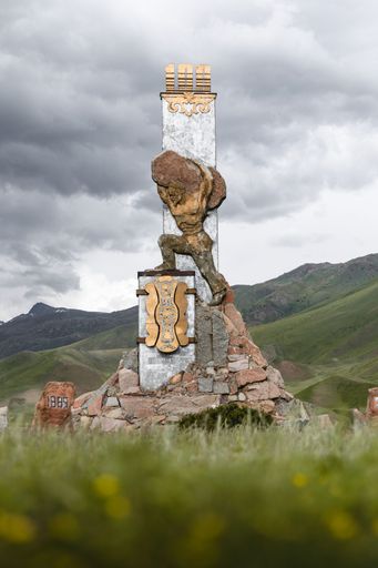 A vertical shot of man statue holding big rock on back in Kojomkul